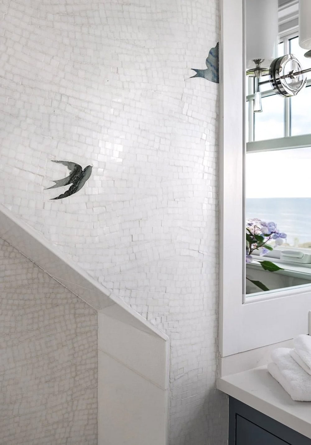 Detail of textured white tile wall with painted swallow bird accents