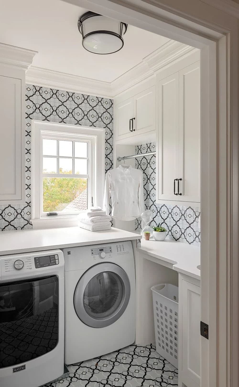Laundry room with patterned tile backsplash and white cabinetry