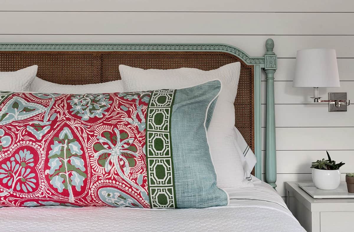 Detail of red and green patterned pillow on a seafoam-blue bed frame