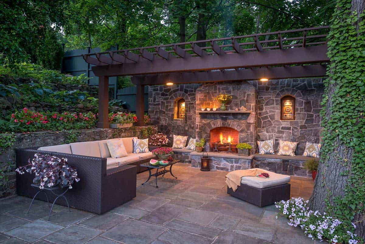 Old-world stone fireplace with pergola on a lush patio retreat