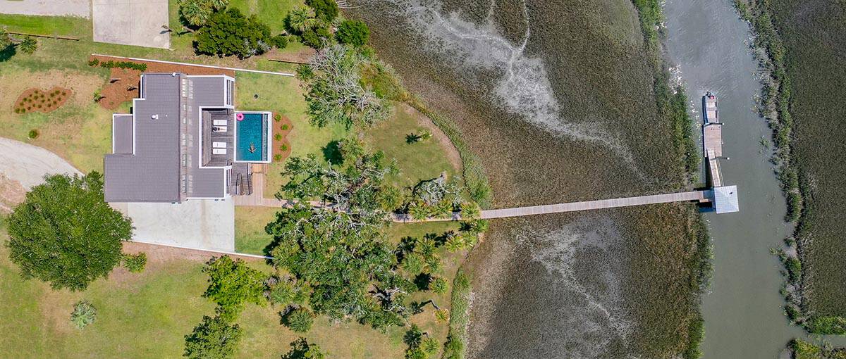 Aerial view of home with marsh, dock, and pool overlooking tidal creek