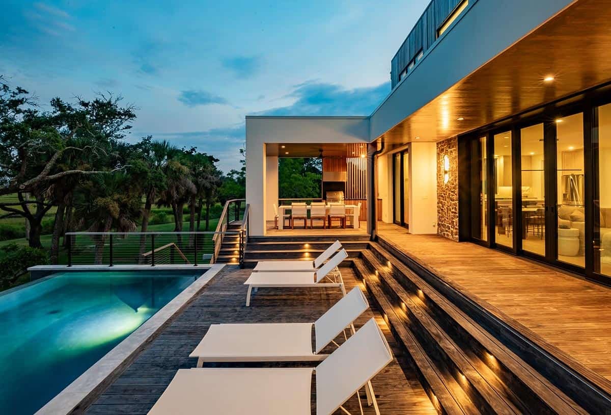 Outdoor pool deck and dining area illuminated at dusk