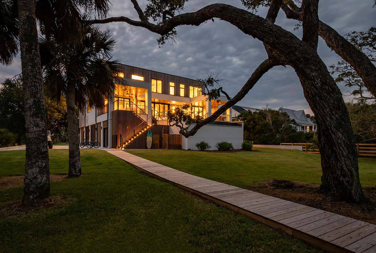 Illuminated modern home exterior at dusk framed by oak trees