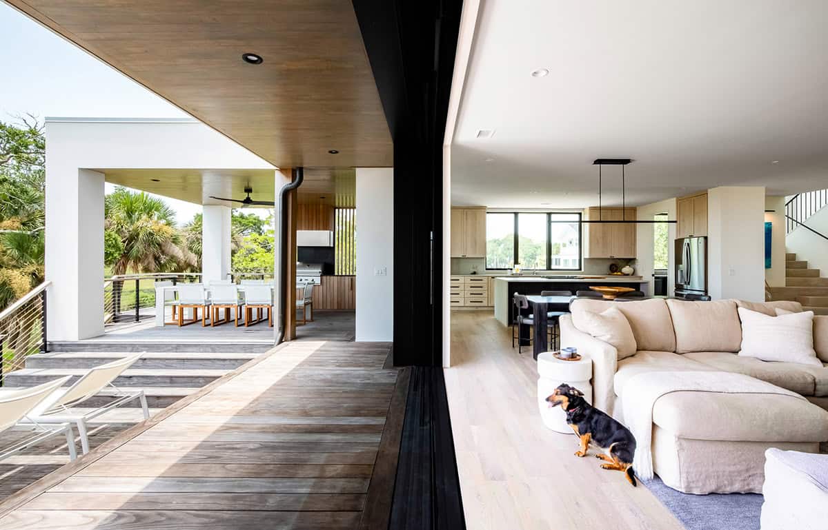 Open-concept living room and kitchen with dog, opening to covered deck