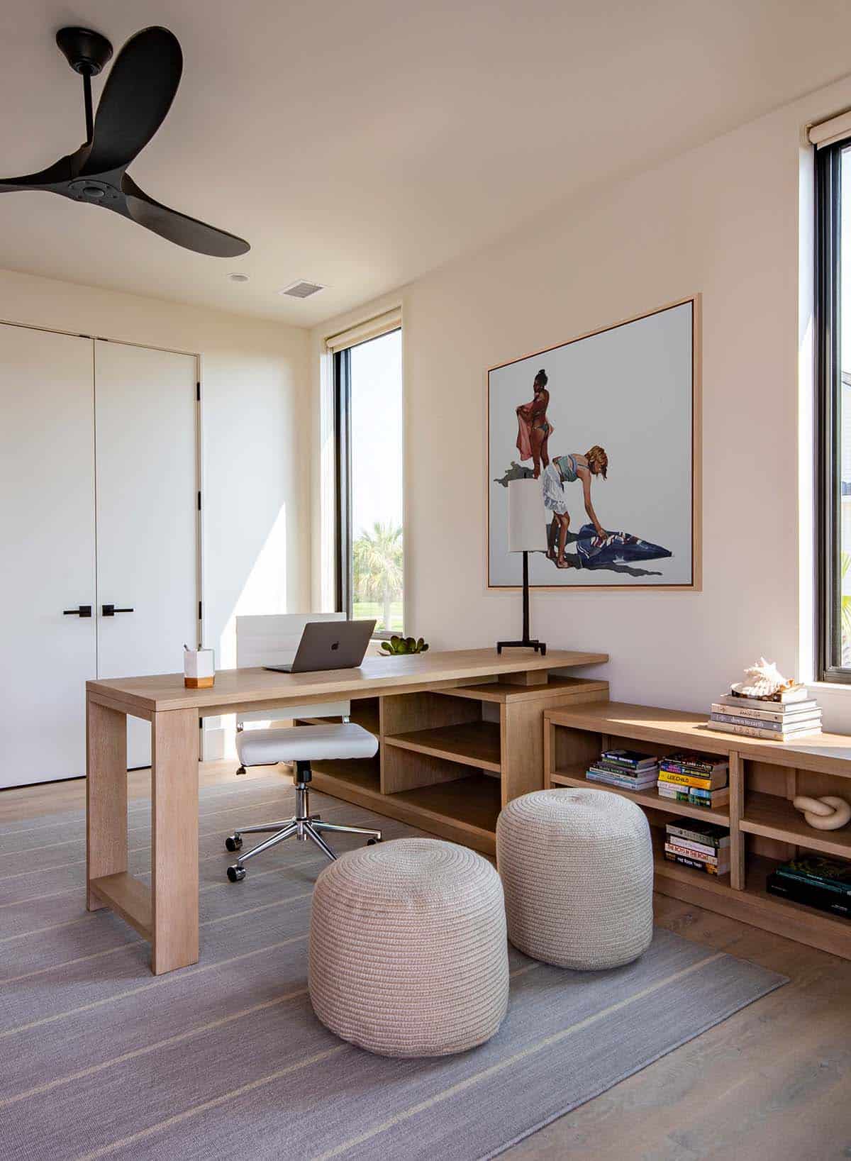 Home office with wood desk, artwork, and woven poufs