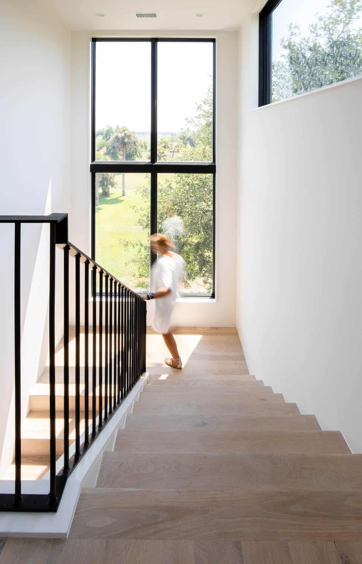 Bright stairwell with tall windows overlooking marsh landscape