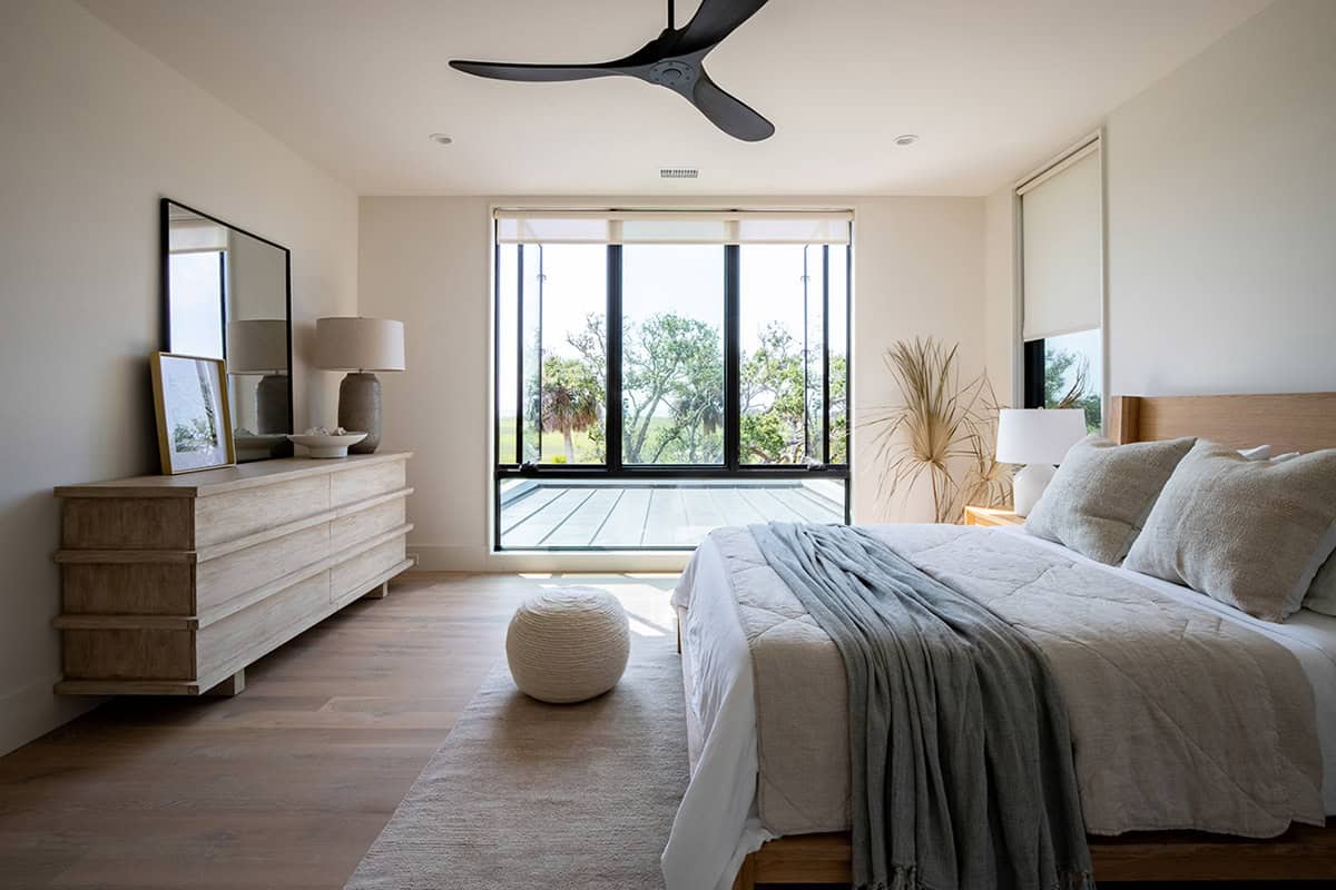 Primary bedroom with wood dresser and floor-to-ceiling windows