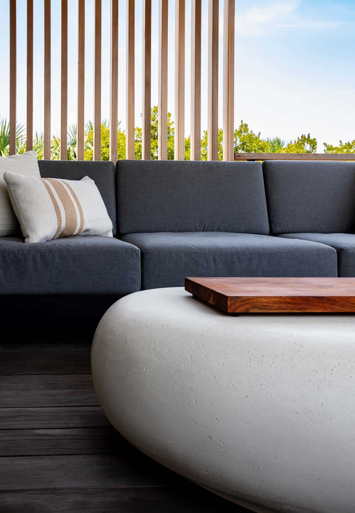 Gray sectional sofa with striped pillow beside wood slat privacy screen