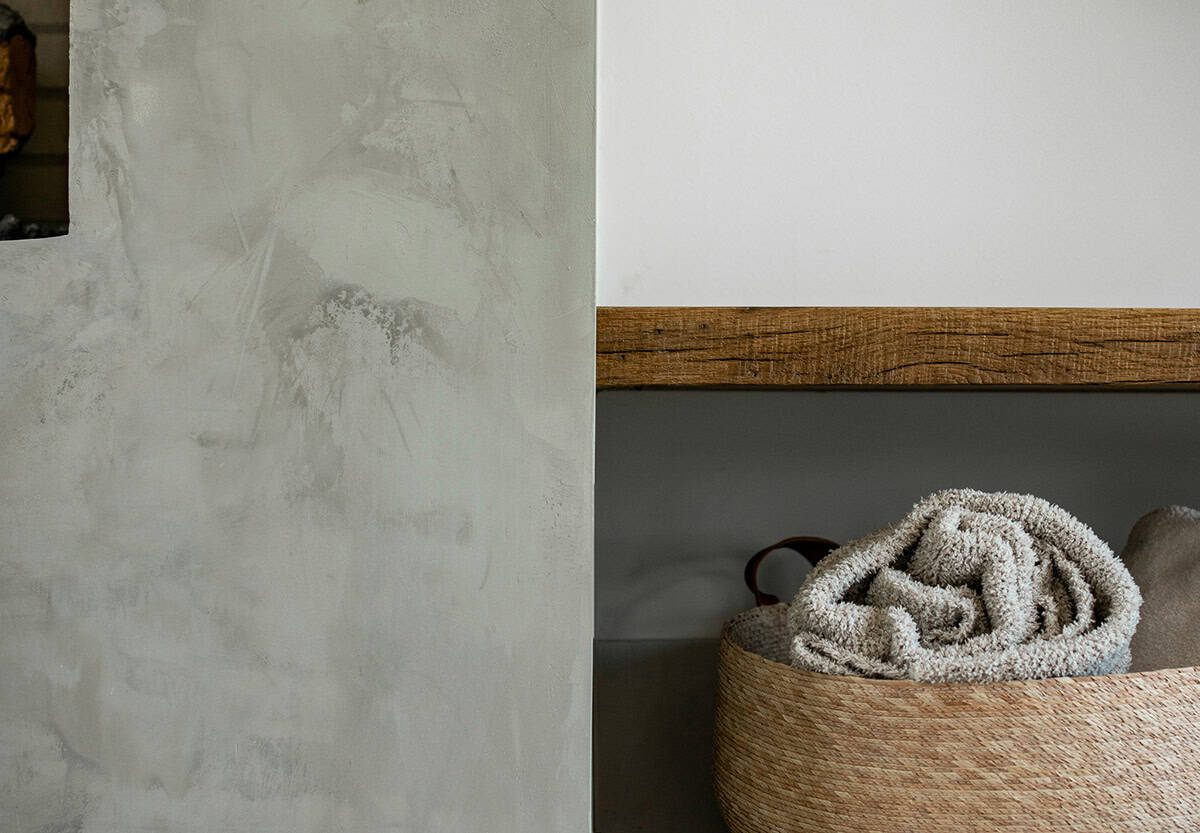 Detail of textured plaster wall and reclaimed wood shelf with folded towels