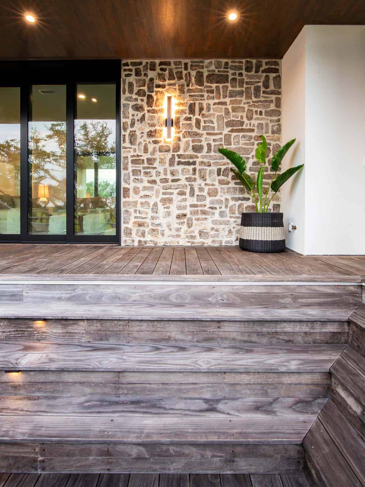Covered entry with stone accent wall, sconce lighting, and potted plant