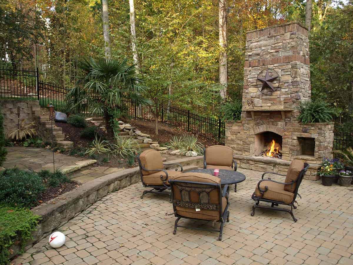 Stacked stone outdoor fireplace with seating area on a paver patio