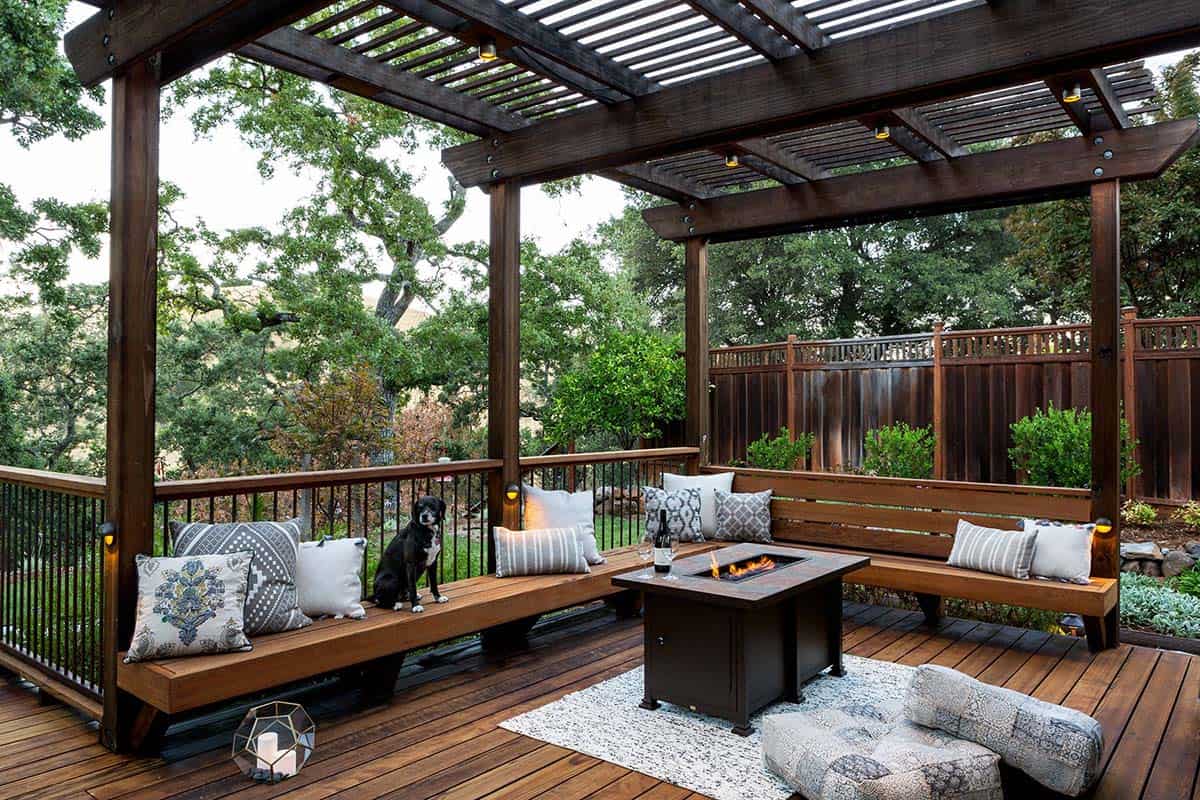 Deck lounge area under wood pergola with built-in bench seating and fire table in Berkeley, California