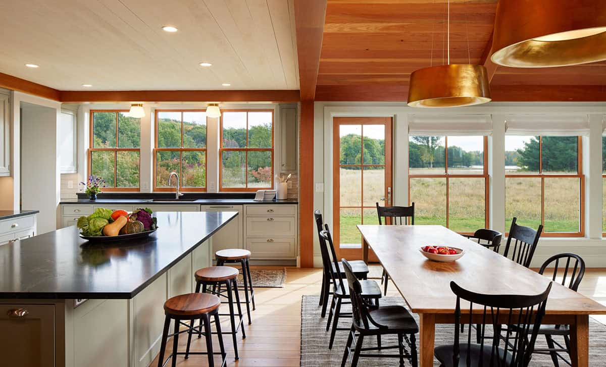 Kitchen and dining area with sage cabinets, black countertops, and meadow views