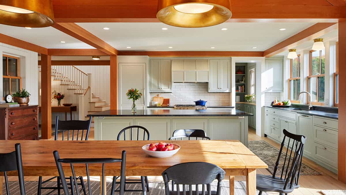 Kitchen with sage cabinets, subway tile, brass pendant lights, and oak dining table