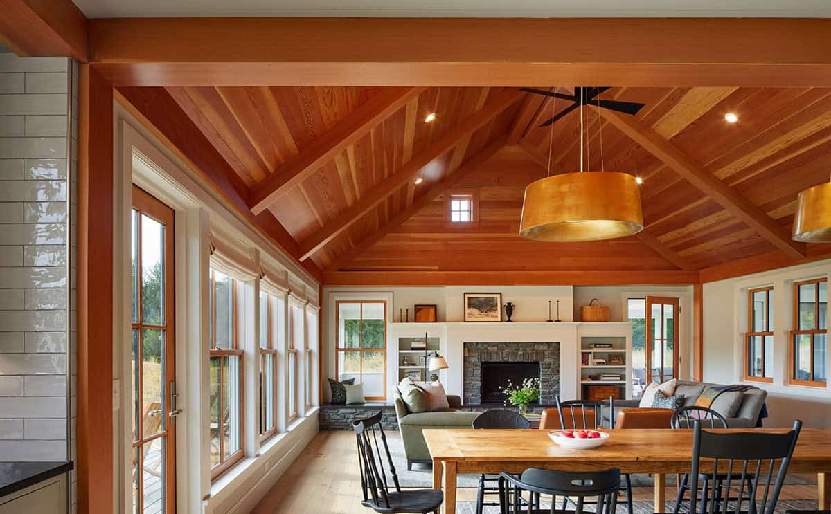 Vaulted living room with wood ceiling beams, stone fireplace, and built-in shelving