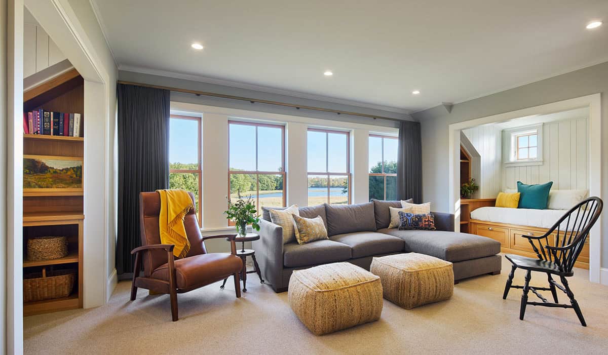 Upstairs sitting area with gray sectional sofa, bookshelves, and lake view