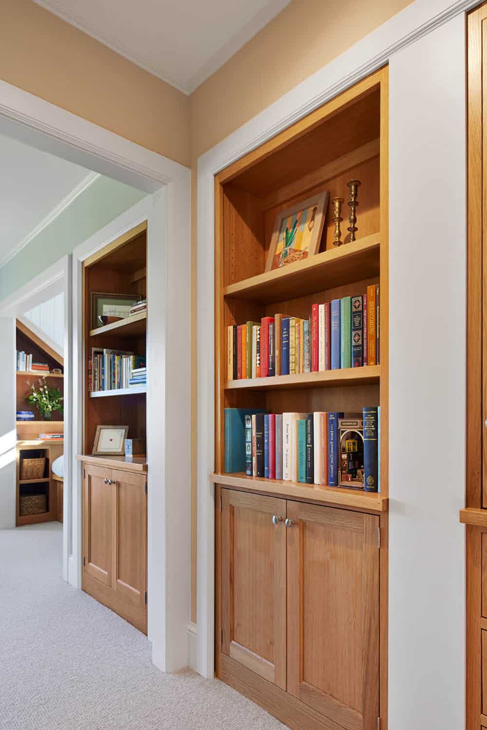 Built-in oak bookshelves in a hallway nook styled with books and framed art