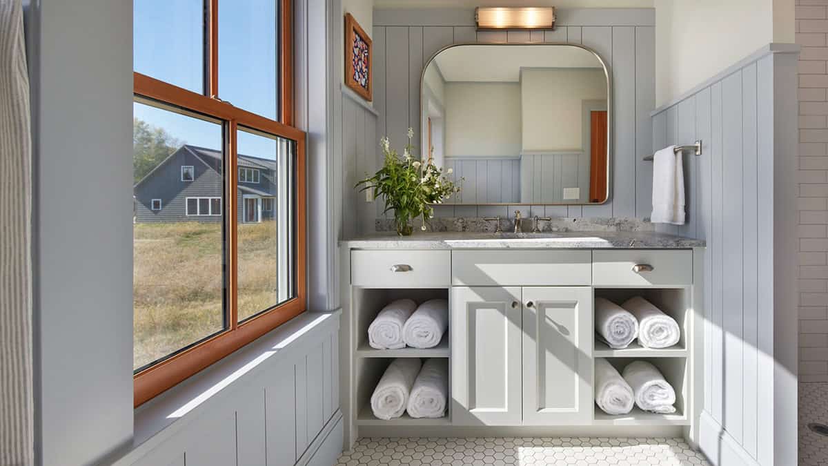 Bathroom vanity with gray shiplap walls, stone counter, and rolled white towels