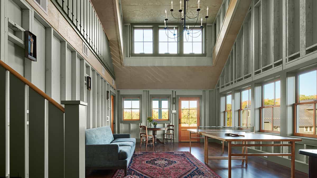 Double-height room with plywood walls, ping-pong table, and seating area under an open loft