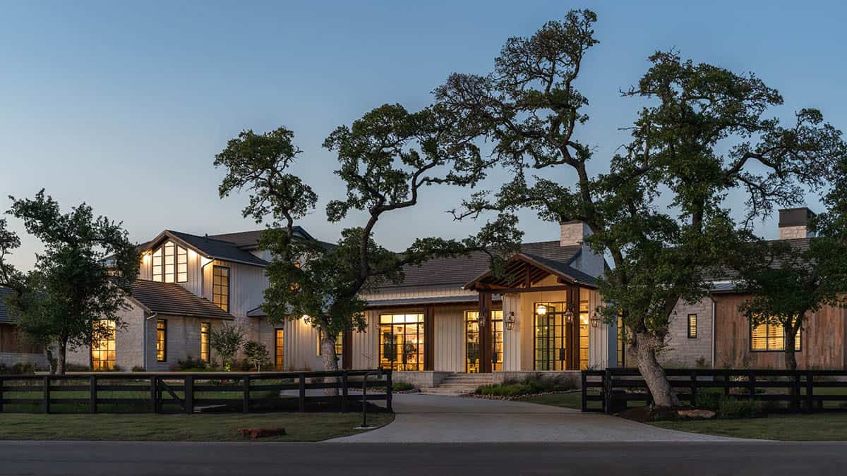 Ranch home at dusk viewed through mature oaks along the driveway