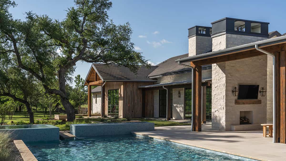Poolside view of stacked stone chimneys and covered outdoor living area