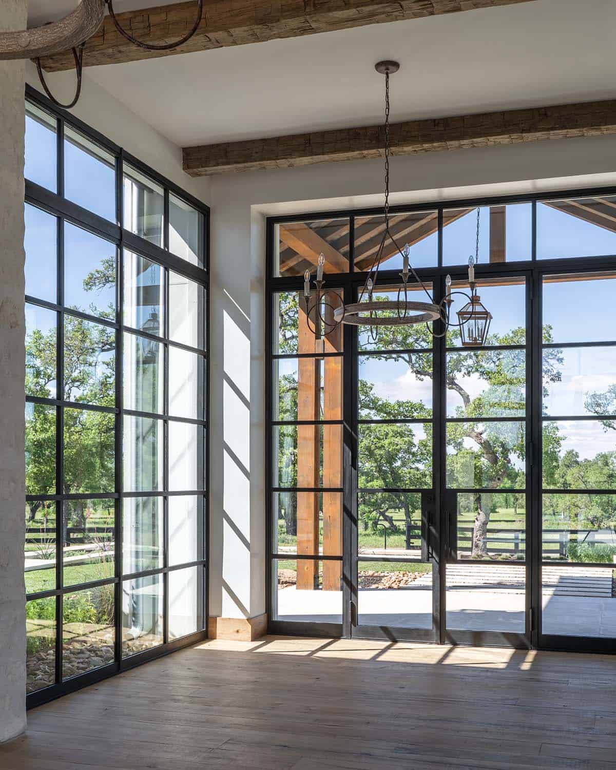 Floor-to-ceiling steel windows and doors opening to the covered entry
