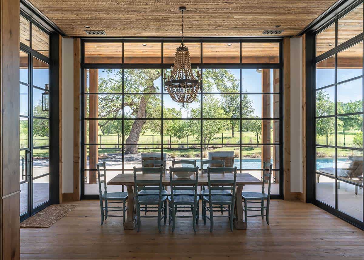 Dining area with beaded chandelier and steel doors overlooking the pool