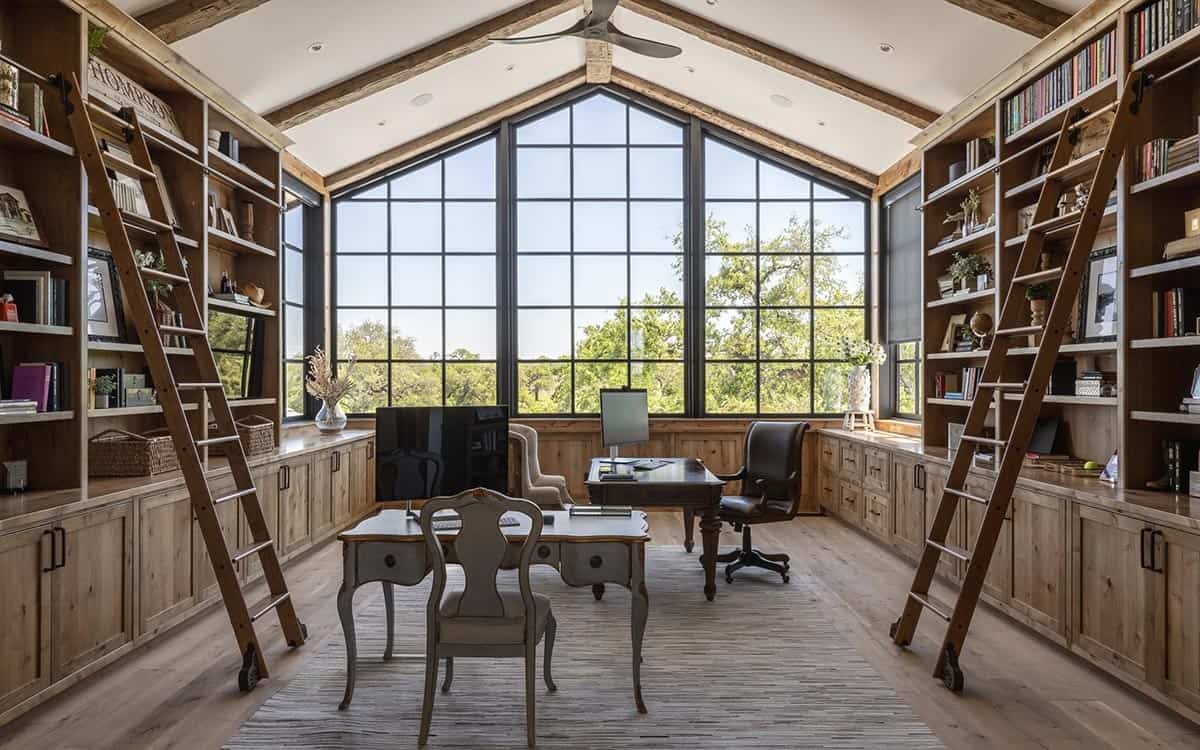 Home office with vaulted ceiling, built-in shelving, and rolling ladders