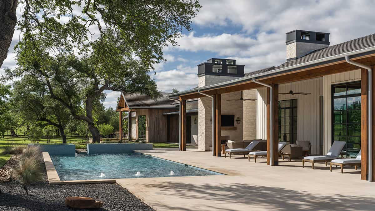Pool and covered patio with dual stone chimneys and wood beams
