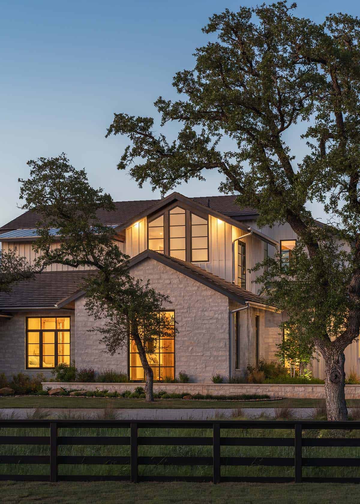 Dusk view of ranch house exterior framed by an oak tree