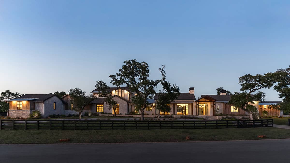Dusk view of the sprawling ranch home nestled among mature oaks