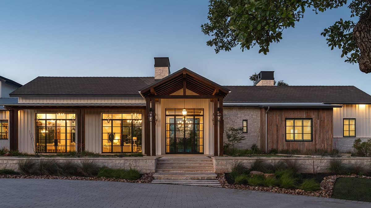 Front entry with gabled wood portico and glass doors at dusk
