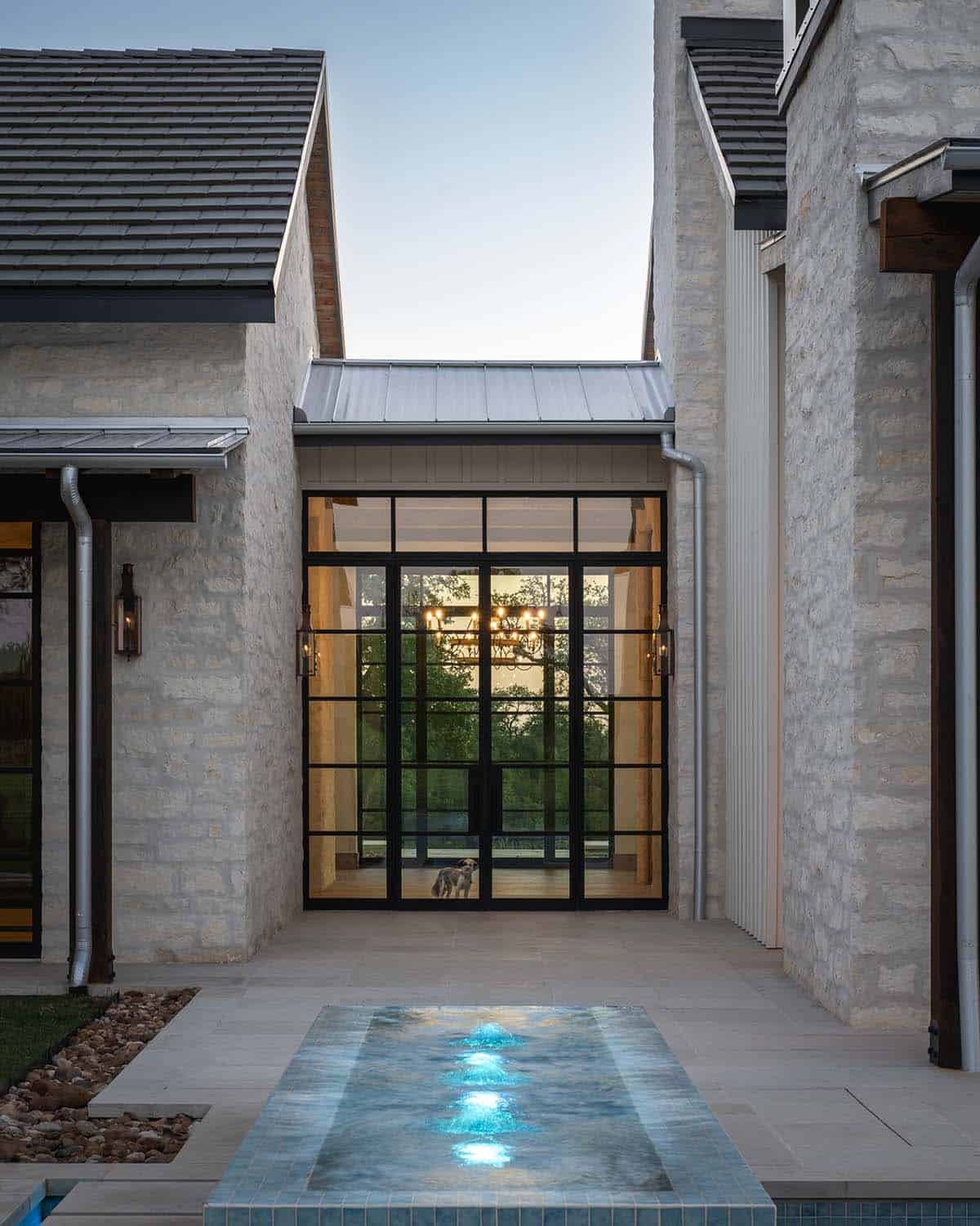 Outdoor courtyard view of steel doors, spa, and a small dog