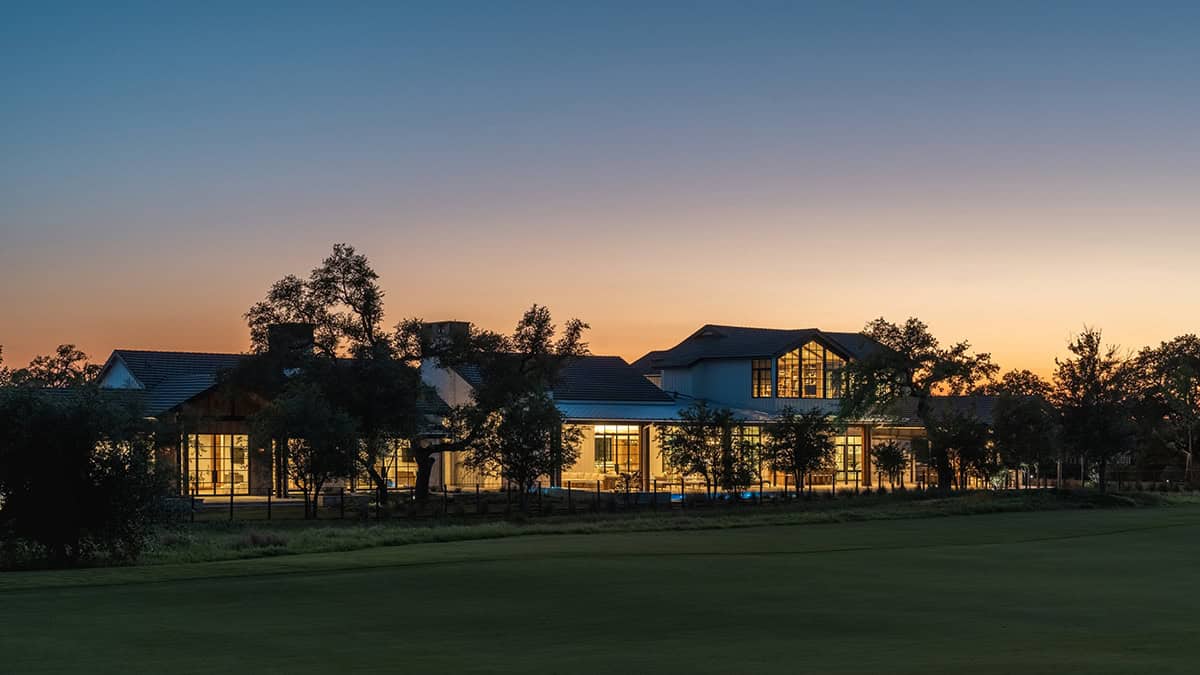 Sunset view of the home with mature oak trees