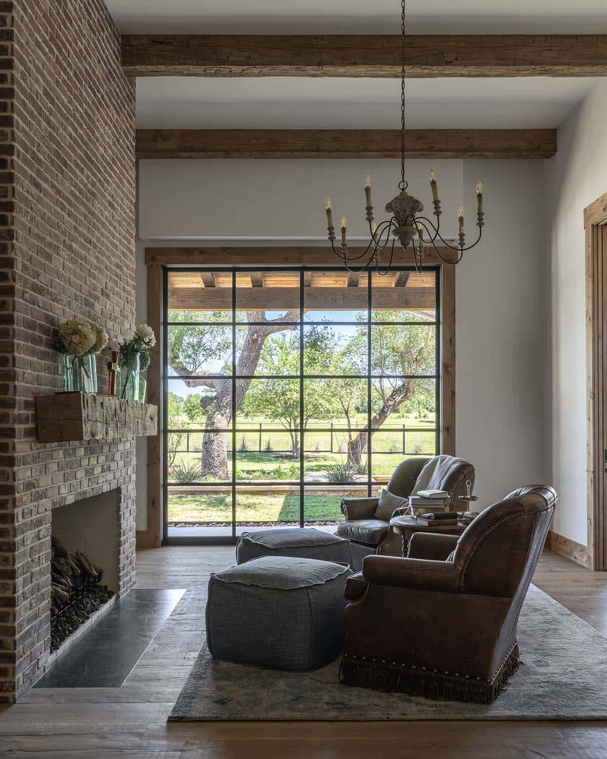 Bedroom sitting area with chairs in front of a brick fireplace and a picture window