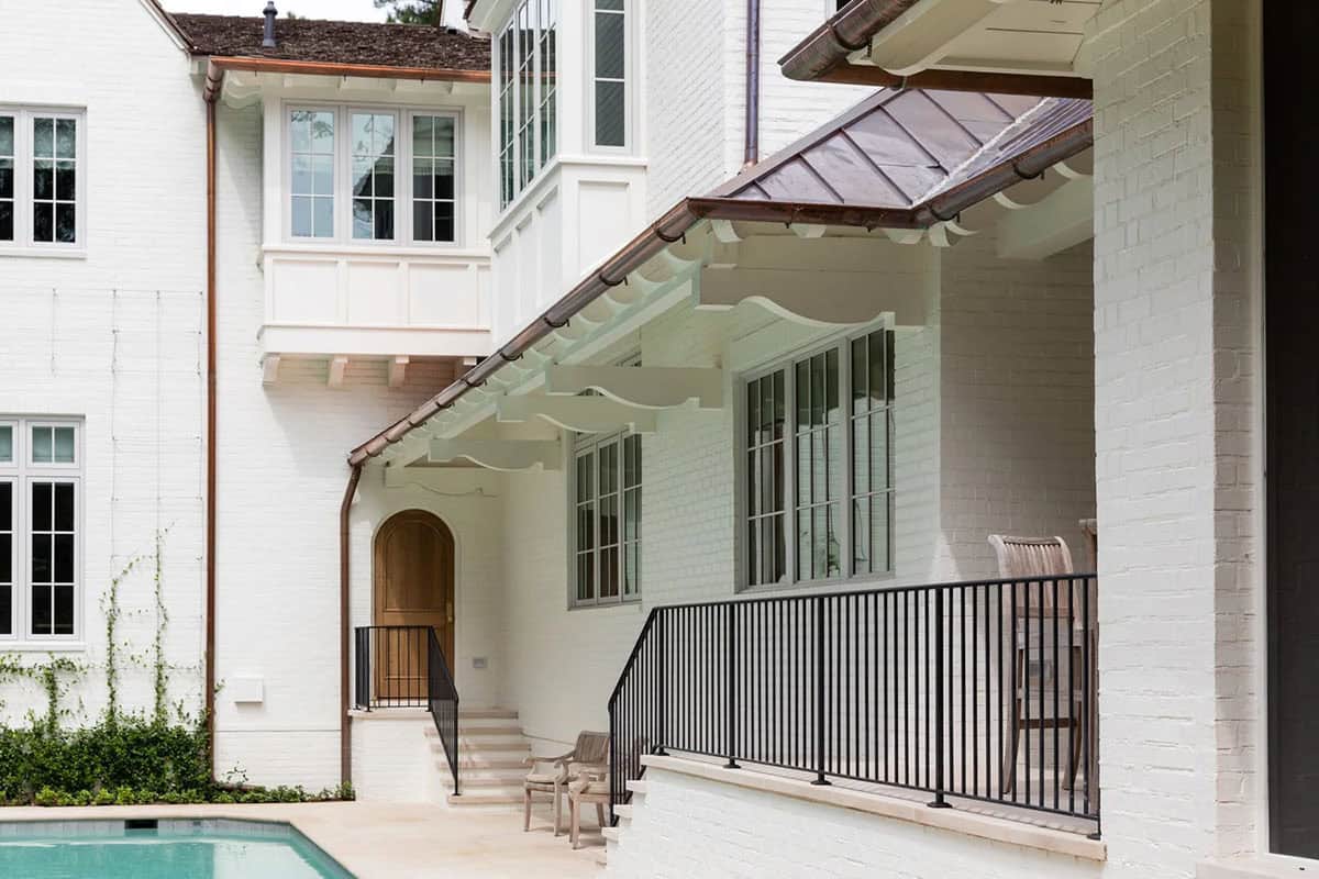 Exterior side view showing copper roof, covered porch, and pool edge