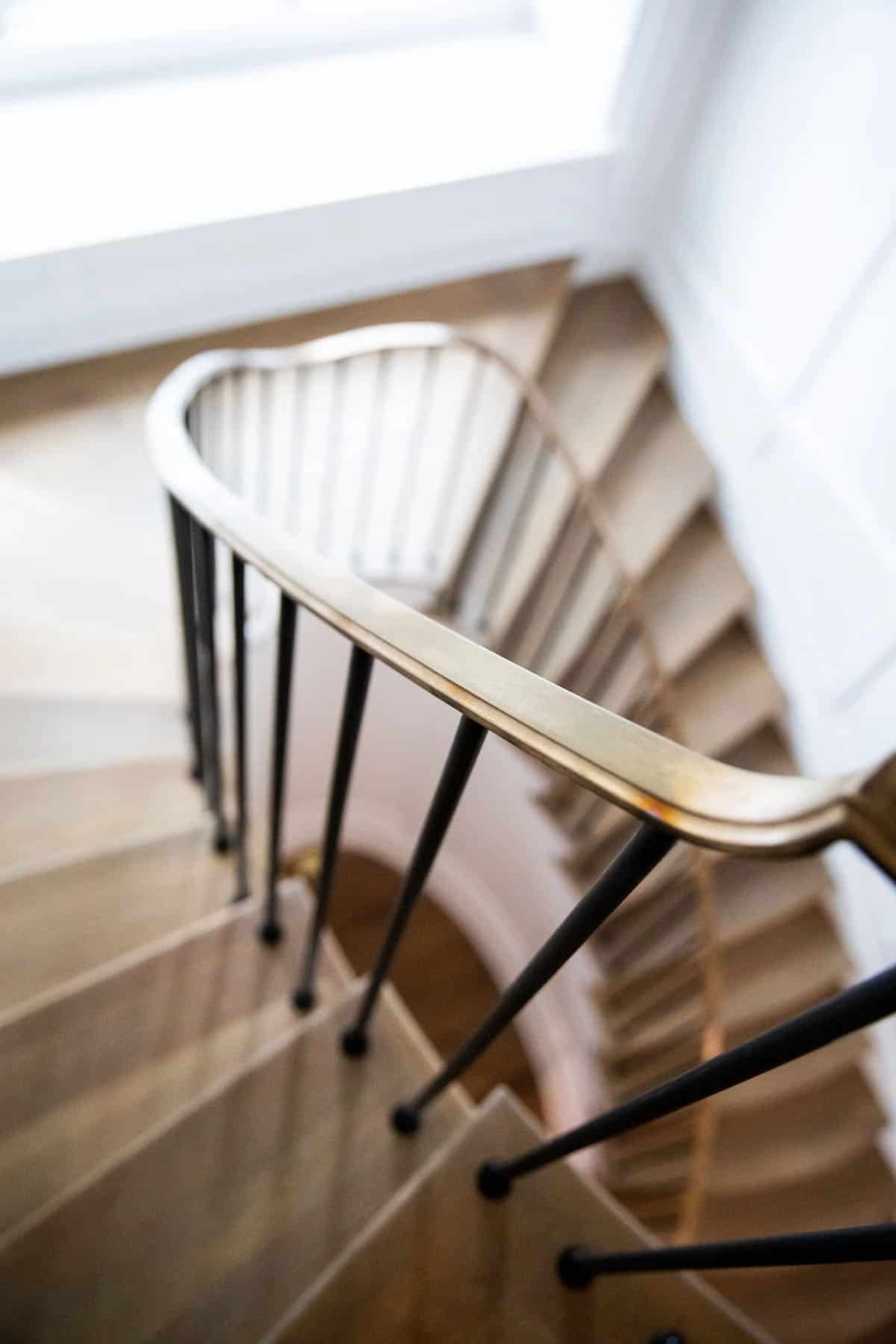 Close-up of spiral staircase brass handrail with black iron balusters