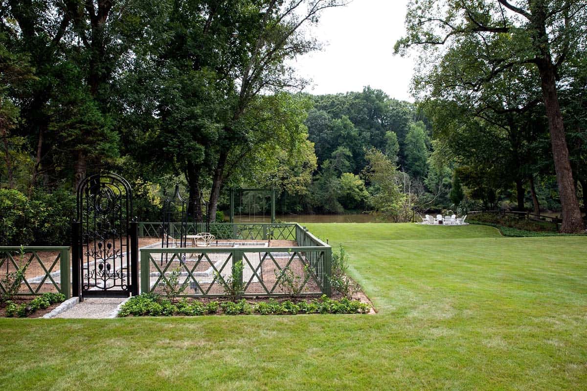 Garden with black iron gate, green lattice fencing, and river view beyond the lawn
