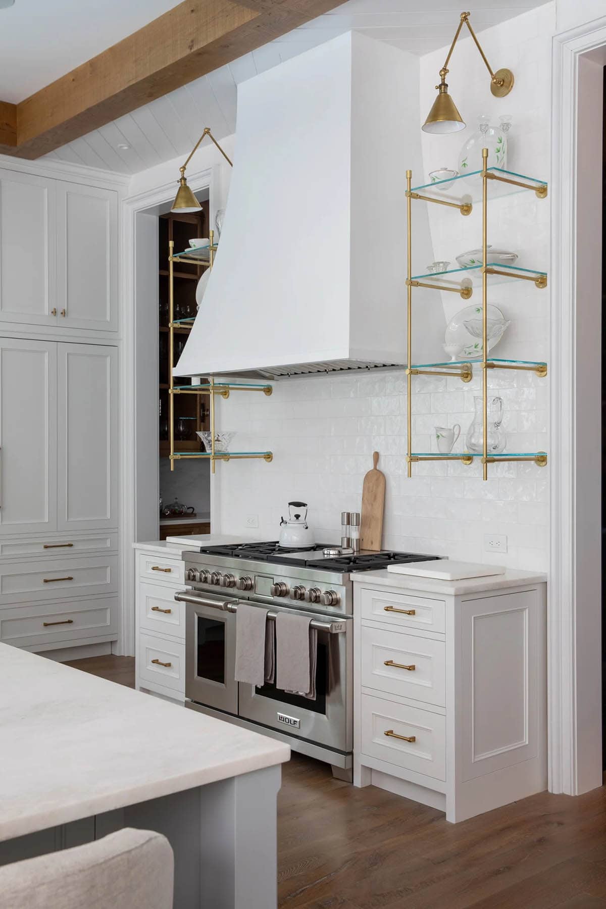 Kitchen range wall with brass wall-mounted glass shelves and stainless steel Wolf stove