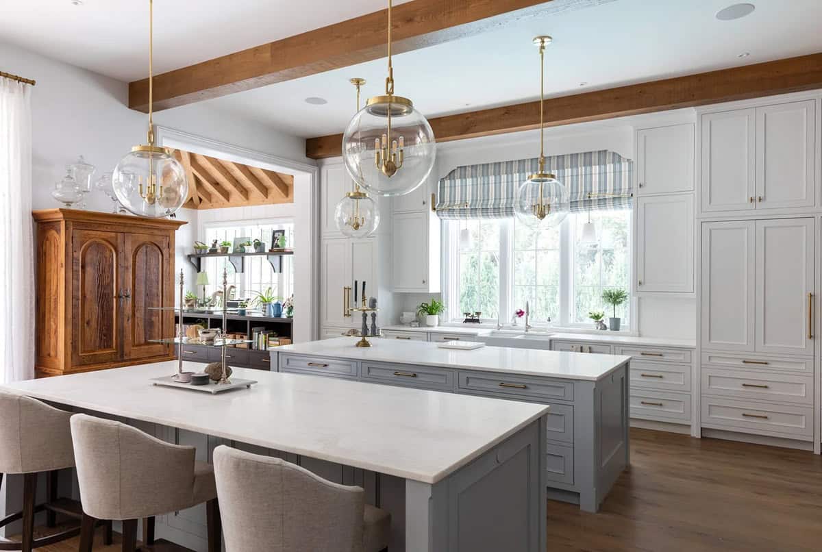 Kitchen with two gray islands, glass globe pendant lights, and wood beam ceiling