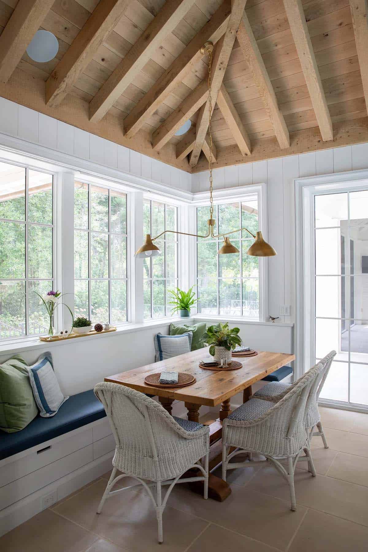 Sunroom breakfast nook with wicker chairs, wood table, and vaulted wood-plank ceiling
