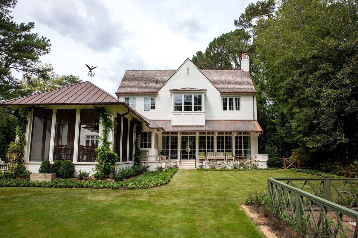 Rear exterior view of the home with screened porch, copper roofing, and manicured lawn