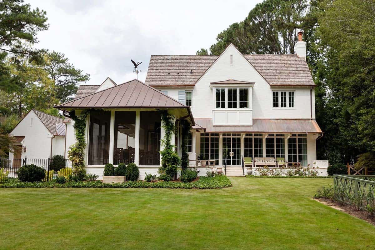 Rear exterior of white brick house with copper roofs, screened porch, and sunroom