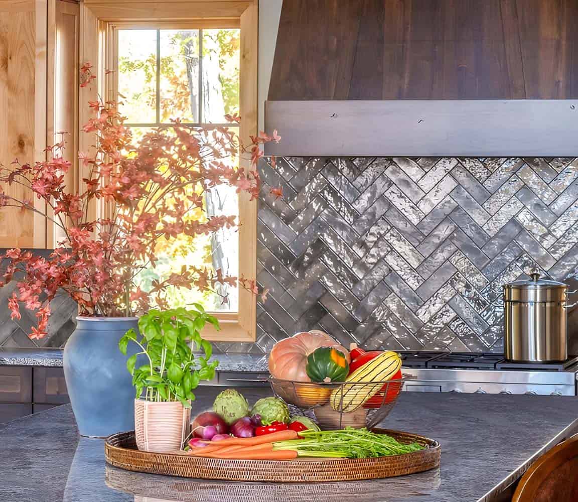 Kitchen counter vignette with fresh vegetables, basil plant, and herringbone metallic tile backsplash