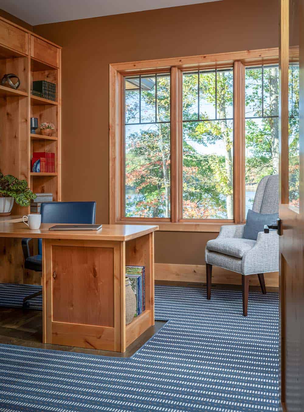 Home office with wood desk, built-in shelving, and large window overlooking the lake