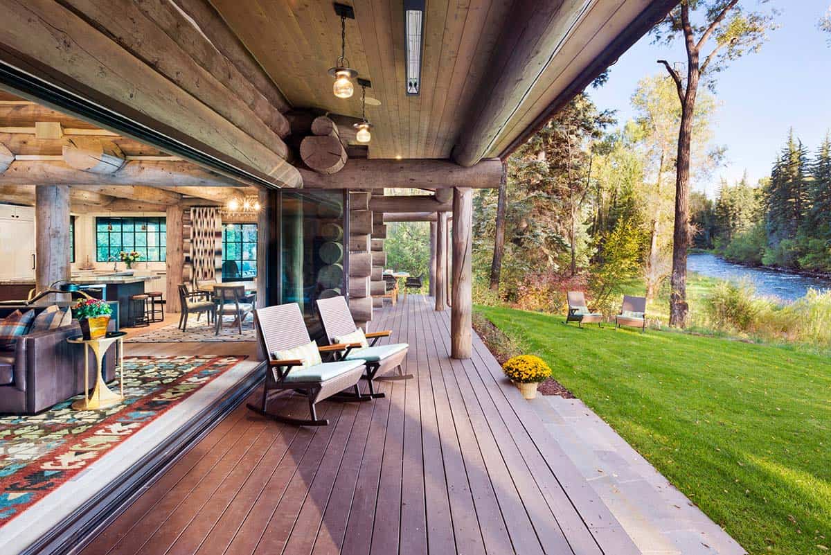 Covered wood deck with rocking chairs overlooking a riverside lawn