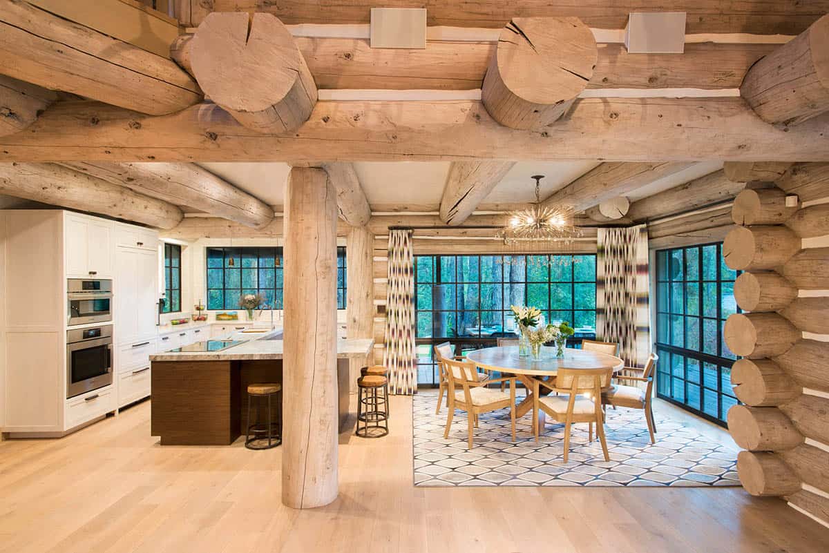 Open kitchen and dining area with log beams and round wood table