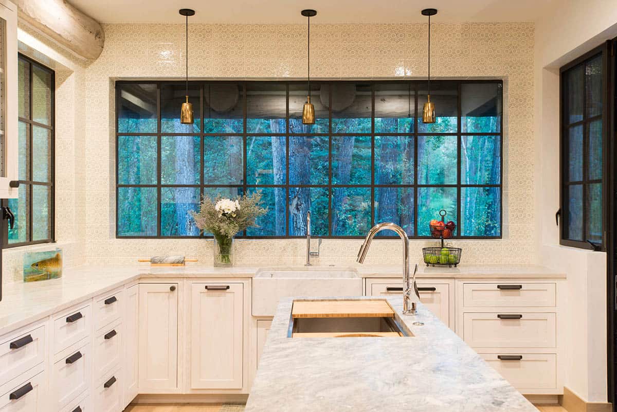 White kitchen with large steel-framed window overlooking trees