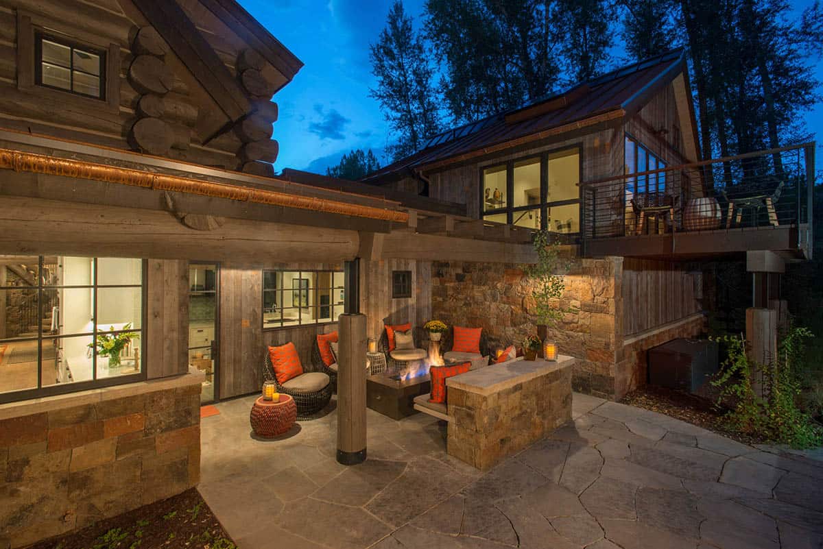Stone patio with fire pit and lounge seating lit at dusk