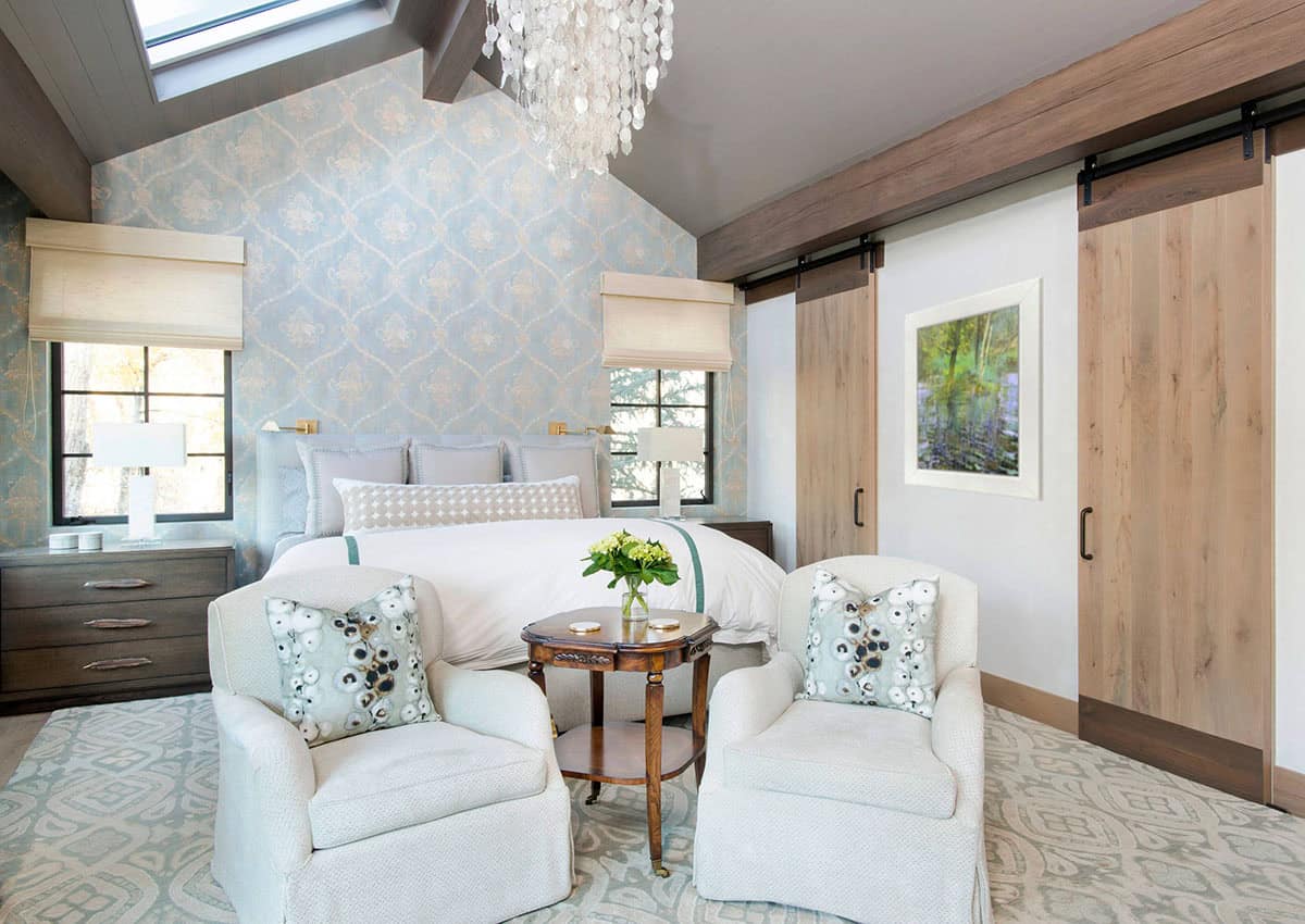 Bedroom with blue floral wallpaper, sliding barn doors, and shell chandelier